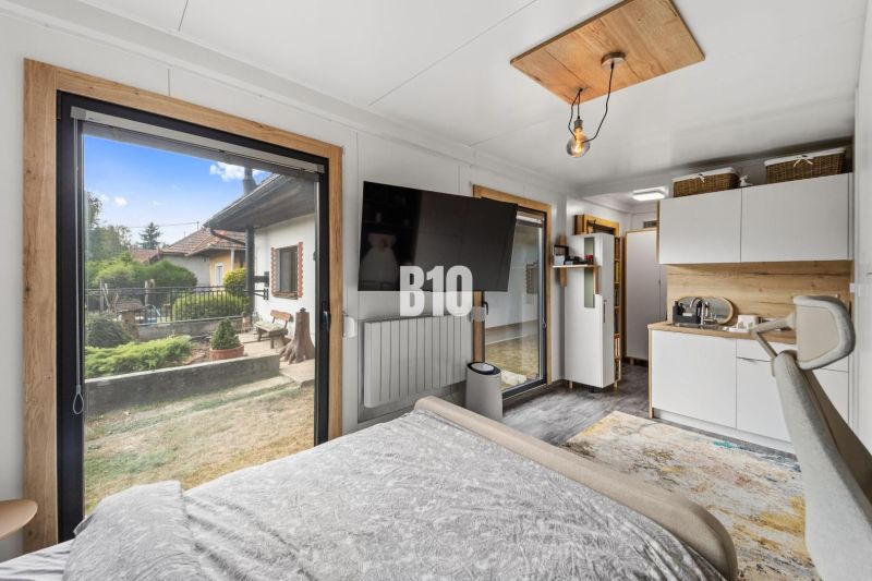 Interior of a family house with a bed, TV, kitchenette, and a view through a large window.