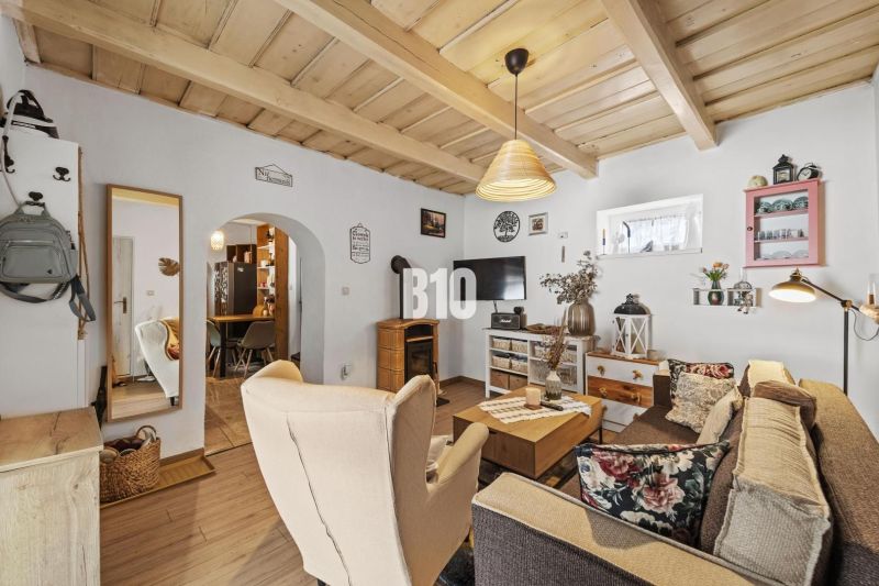 Interior of a family house with a wooden decor floor, furniture, and a ceiling-mounted fireplace.