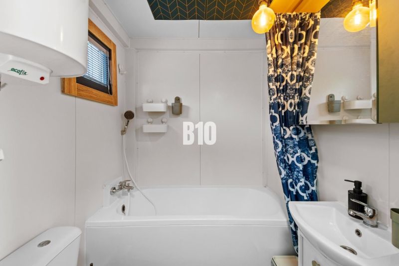 A bathroom in a family house with a bathtub, a sink, and a colorful shower curtain.