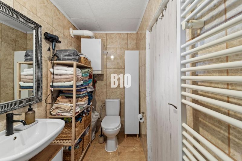Bathroom in a family house, with a bathtub, sink, and tiles in natural shades.