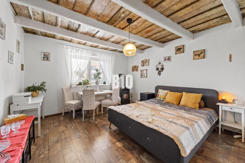 A family house with a wooden decor floor, a double bed, and a dining area.