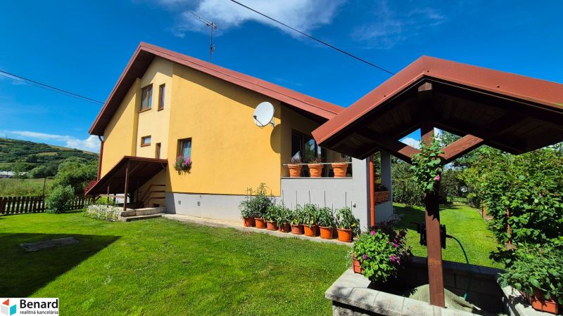 A family house in Podolínec with a garden, grassy plot, and wooden gazebo structure.
