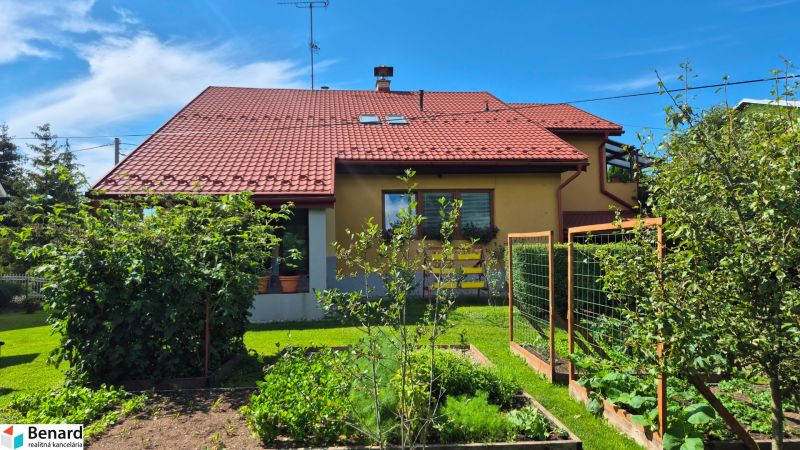 A family house in Podolínec with a red roof, a garden, and fruit trees.