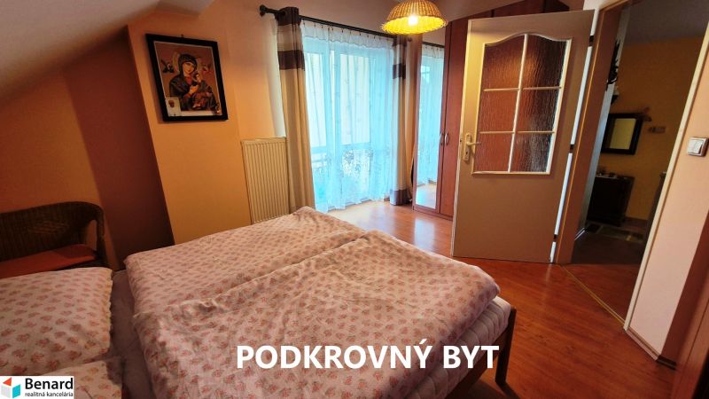 A bedroom in a family house with a wooden decor floor and balcony doors.