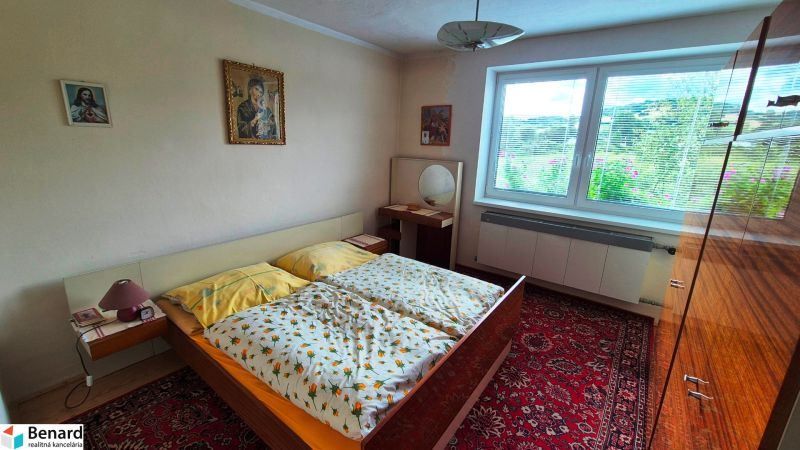 Bedroom in a family house with a patterned carpet, furniture, and paintings on the wall.