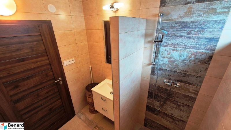 A bathroom in a family house with ceramic tiles and a shower with wood decor.