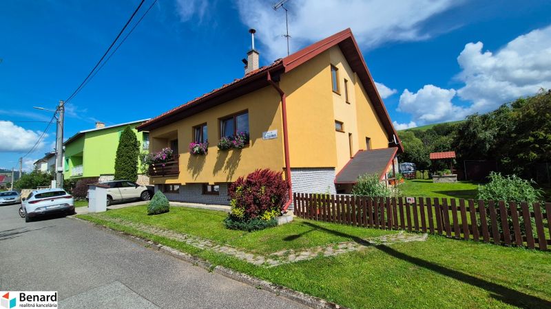 A family house in Podolínec with a garden and a yellow facade, surrounded by greenery.
