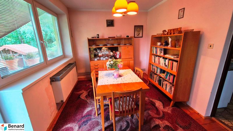 Dining room in a family house with wooden furniture and a large window.