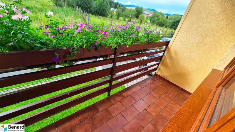 A balcony of a family house in Podolínec with flowers and a view of greenery.