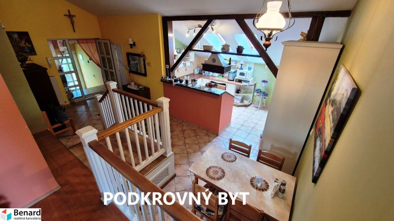 Attic apartment with a dining table, kitchen, and staircase, floor with wood decor.