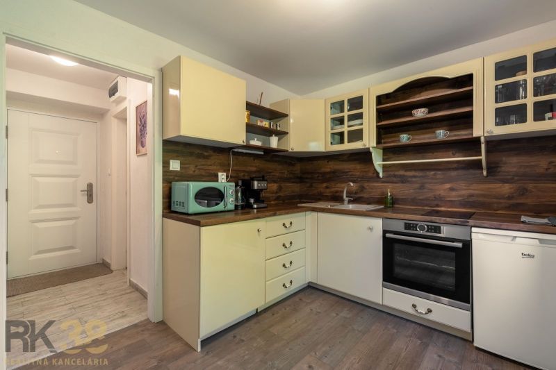 A kitchen in a studio apartment with wooden decor and light furniture.