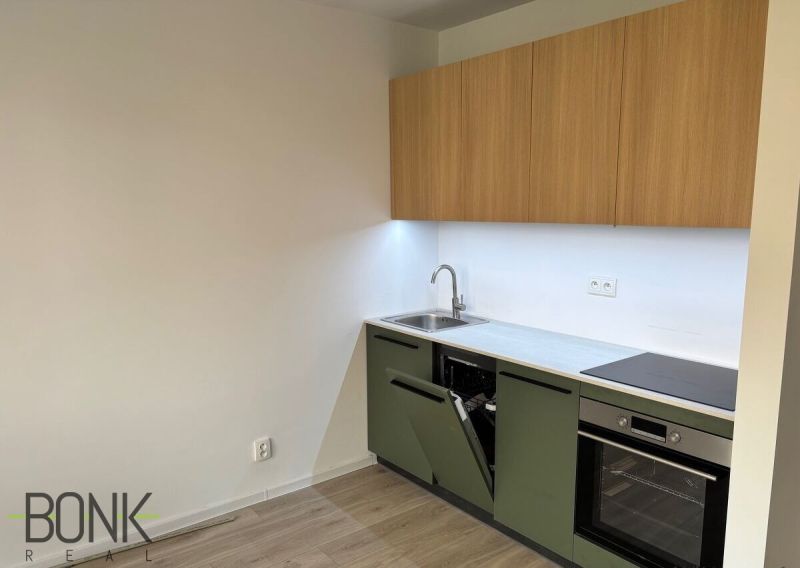 A kitchen in a 2-room apartment with built-in appliances and a floor with a wooden decor.