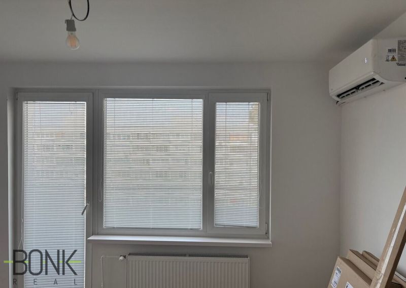 Interior of a 2-room apartment with air conditioning, horizontal blinds, and a radiator.