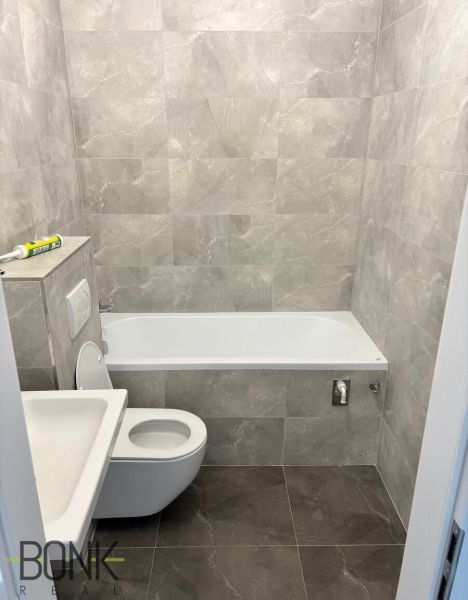 Bathroom in a 2-room apartment with gray tiles and sanitary ware, simple design.