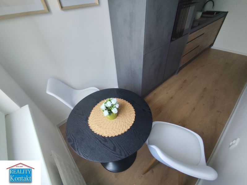 Dining area with a black table and white chairs in a three-room apartment.