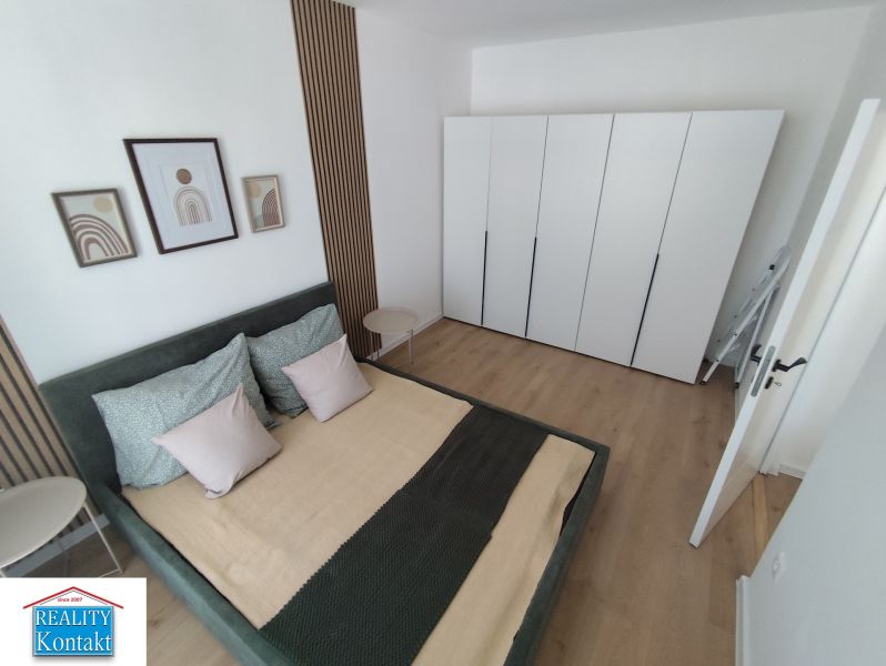 Bedroom in a 3-room apartment with wood-patterned flooring and a large wardrobe.