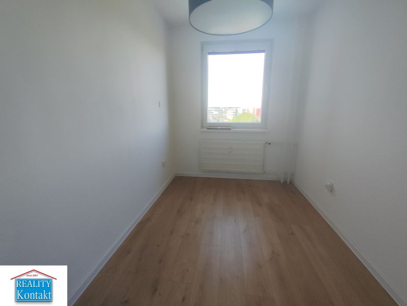 A room with a wooden decor floor and a window in a 3-room apartment.