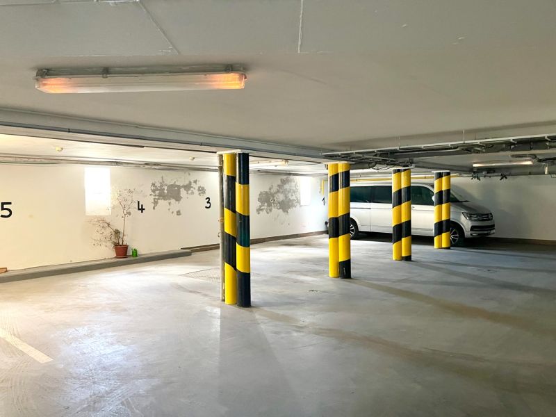 Parking in the basement of a building with numbered spaces and yellow-black columns.