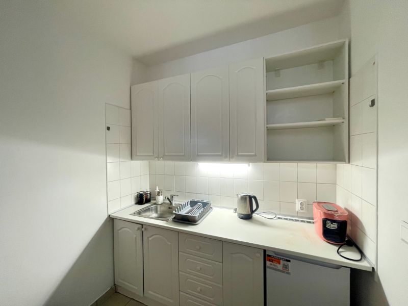Office kitchen equipment with cabinets, sink, electric kettle, and dishwasher.