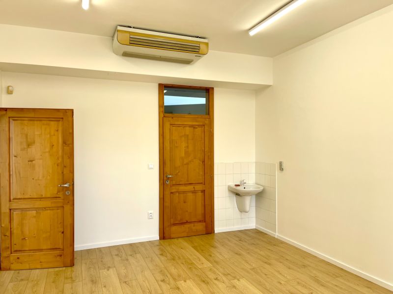 Offices with wooden doors, light walls, and a floor with a wooden design.