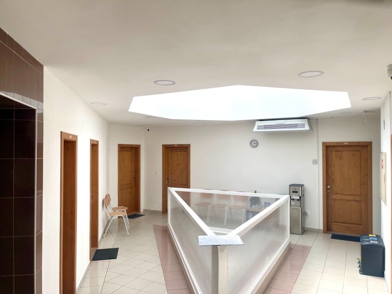 Hallway in the office with doors, skylight, chairs, and a water dispenser.