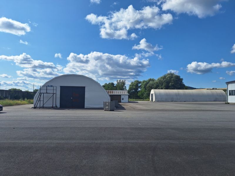 Warehouses and halls in Ličartovce with a blue sky and white clouds.