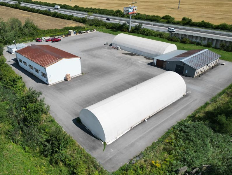 Warehouses and halls in Ličartovce with metal roofs by the main road.