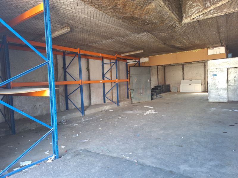 Warehouses and halls with empty shelves, concrete floor, and metal racks.