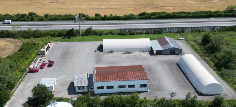 Warehouses and halls in Ličartovce near the highway, with parking and adjacent greenery.