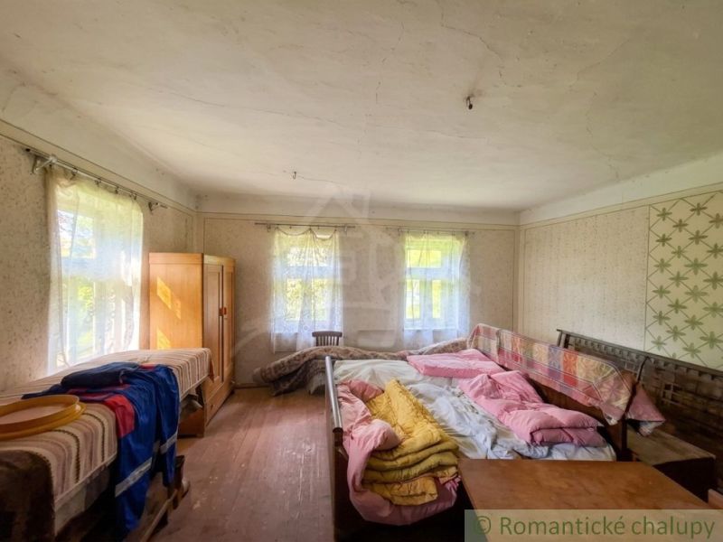 Traditional interior of a family house with beds and windows with delicate curtains.