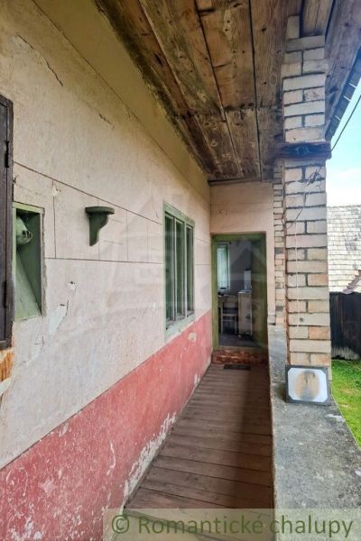 Entrance porch to a family house in Dobroč with a wooden decor and a brick wall.