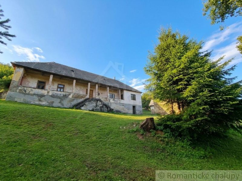 A family house in Dobroč with an extensive lawn and trees on a sloping plot.