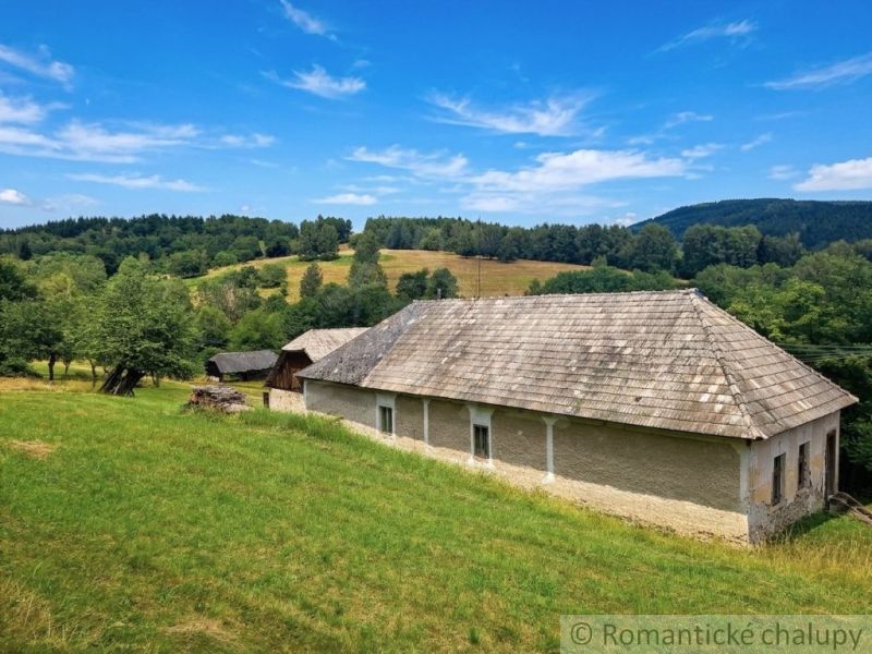 A family house in Dobroč with a wooden roof surrounded by nature and meadows.