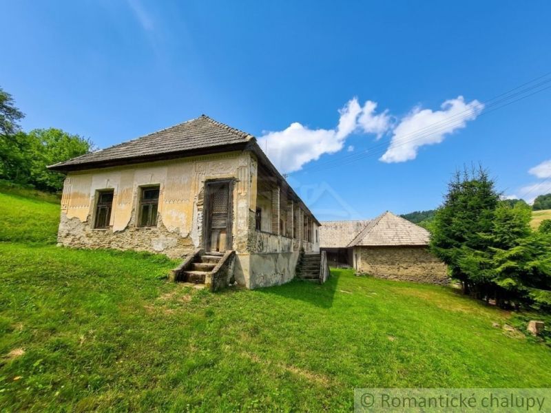 A family house in Dobroč with a historic facade, surrounded by a green meadow and a blue sky.