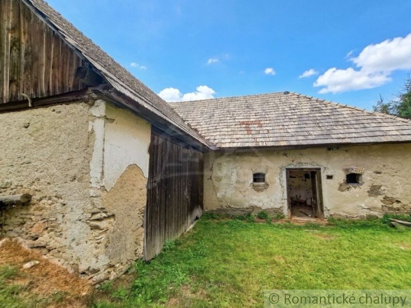 A family house in Dobroč with a stone facade, wooden cladding, and a shingle roof.