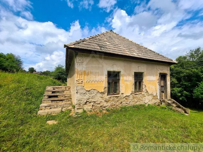 Old stone family house in Dobroč with damaged plaster and a tile roof.