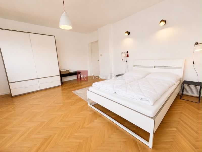 A bedroom with a large bed, a wardrobe, and a floor with a wooden decor in a 3-room apartment.