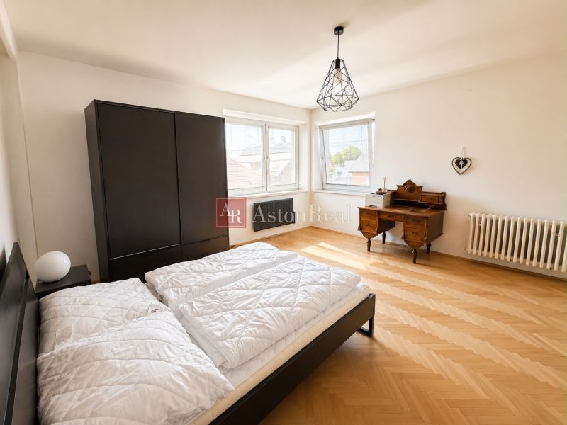 A bedroom in a 3-room apartment with a wooden decor floor and black furniture.