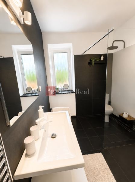 Bathroom in a 3-room apartment with black tiles, a shower corner, and a white sink.