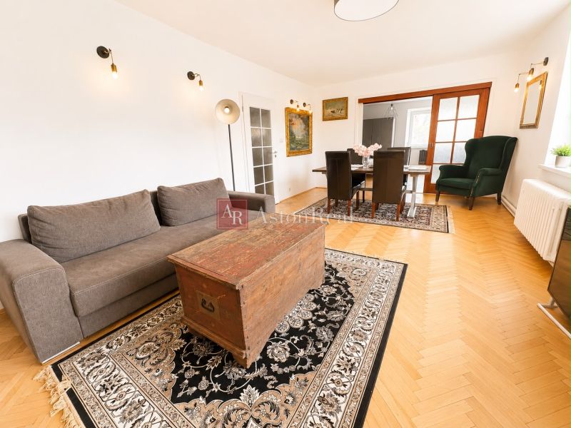 Living room with wood-patterned flooring, a comfortable couch, and a coffee table in a three-room apartment.