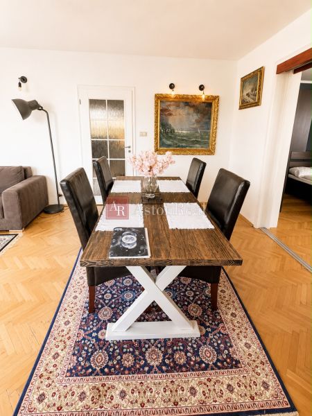 Dining area in a three-room apartment with a wooden decor floor and a carpet.