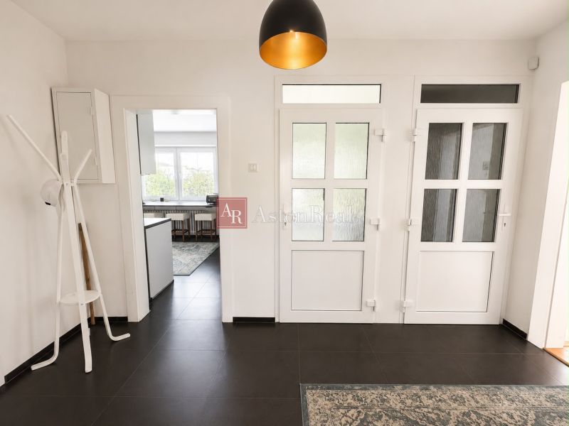 A hallway in a 3-room apartment with white doors and dark tiles on the floor.
