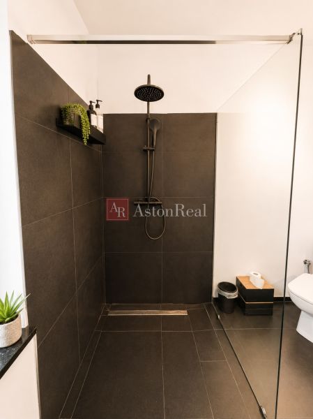 A bathroom in a 3-room apartment with dark tiles and a shower corner.