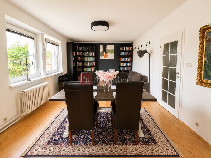 Living room with a bookshelf, wooden decor flooring, and a carpet in a three-room apartment.