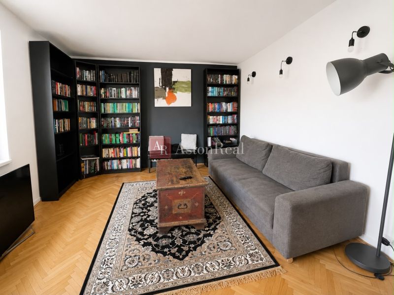 Living room with a bookshelf and a gray sofa in a 3-room apartment, floor with wood decor.