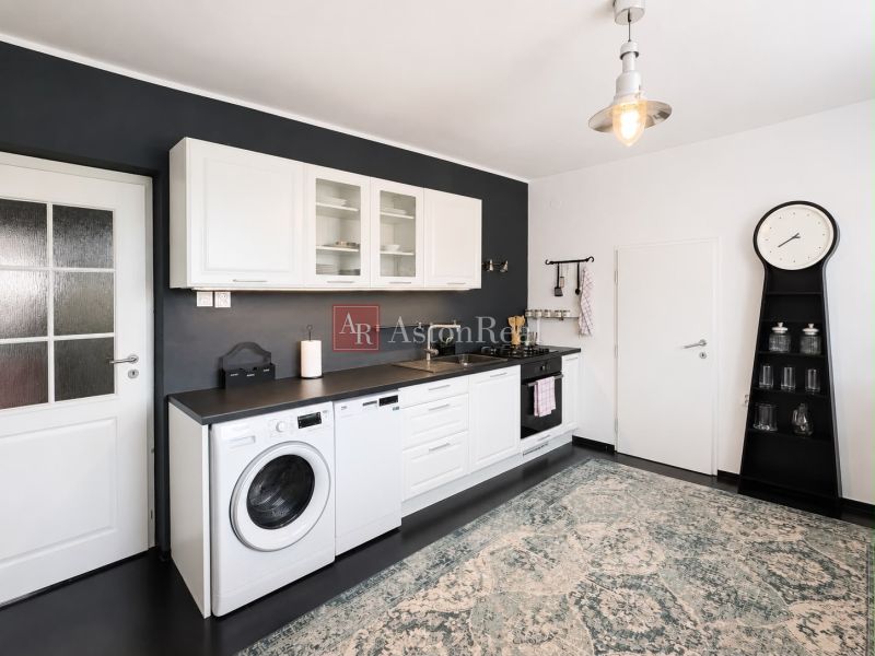 A kitchen in a 3-room apartment with a black wall, white cabinets, and a carpet.
