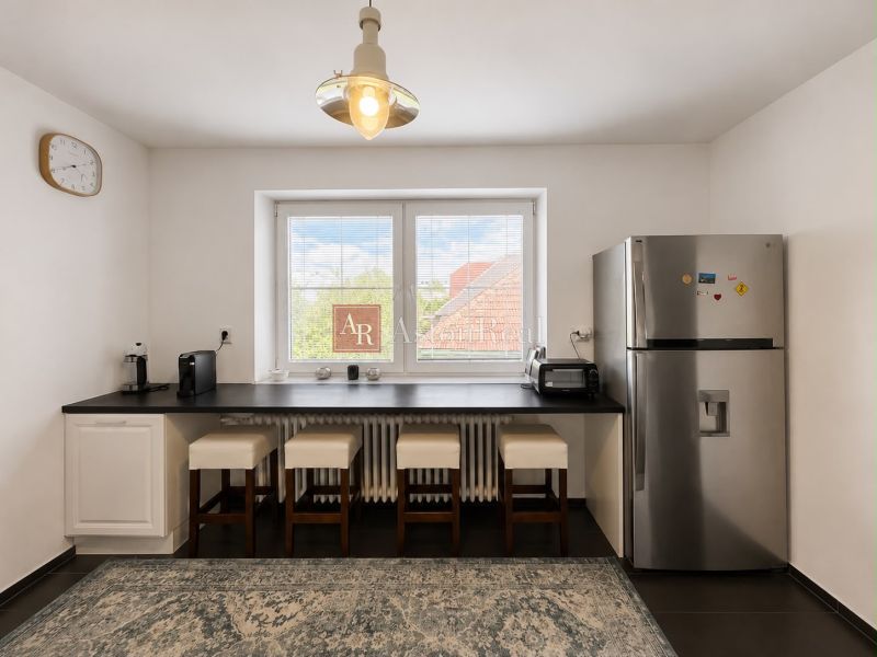 A kitchen in a 3-room apartment with a refrigerator, a bar counter, and four chairs.