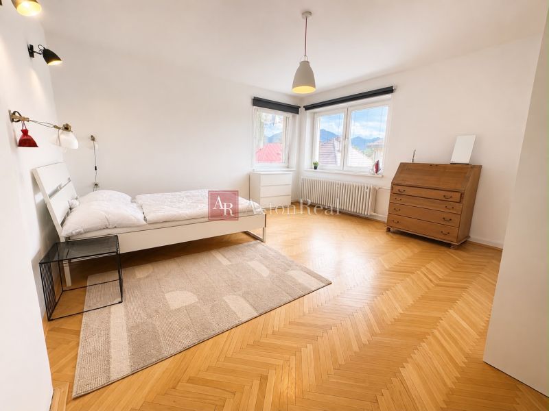 A bedroom in a 3-room apartment with a bed, a dresser, and a floor with a wooden decor.