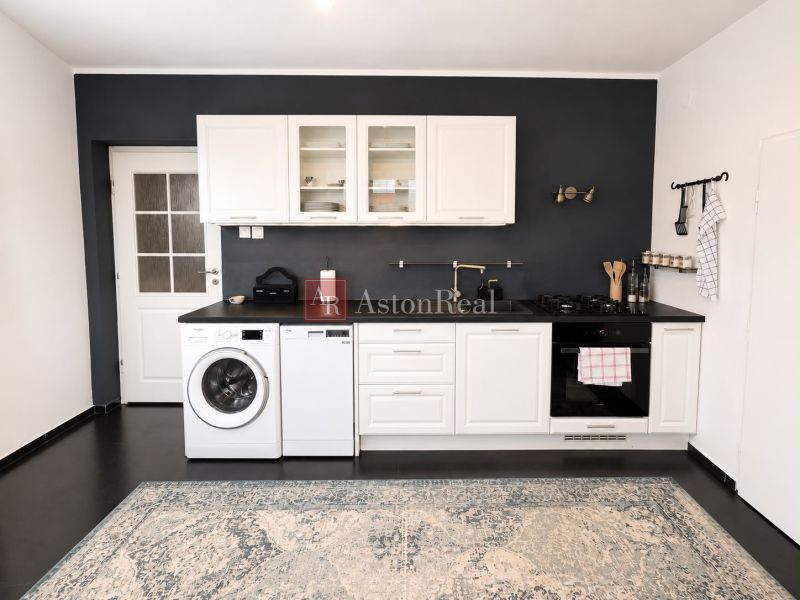 A kitchen in a 3-room apartment with white cabinets and a dark wall.
