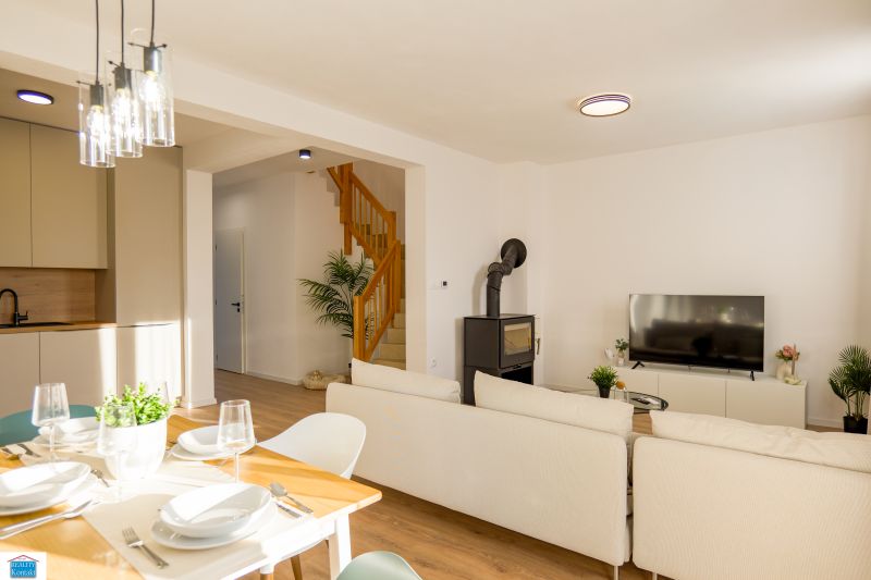 Dining room and living room with a fireplace and wood-patterned flooring in a family house.